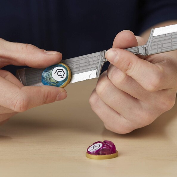Deux mains tenant l’épée grise et les pierres d’infinité bleue et violette du coffret Avengers