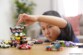 Petit enfant asiatique empilant des petits véhicules colorés les uns sur les autres sous forme de tour sur une table de salle à manger