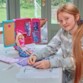Enfant utilisant l'armoire Barbie avec poupée et tissus sur table
