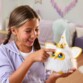 Peluche électronique Furby tenue par une fillette touchant le capteur lumineux, mise en situation